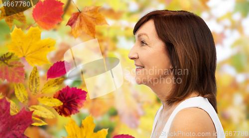 Image of profile of smiling senior woman over autumn leaves