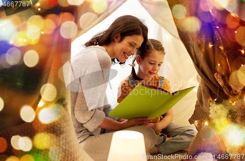 Image of happy family reading book in kids tent at home