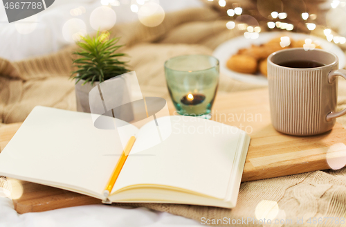 Image of diary, tea and candle in holder at home