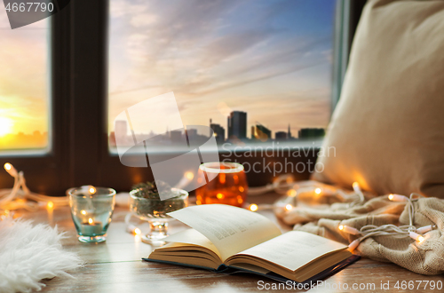Image of book, garland lights and candles on window sill