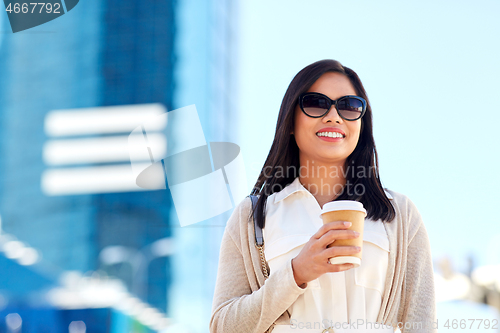 Image of smiling woman with takeaway coffee cup in city