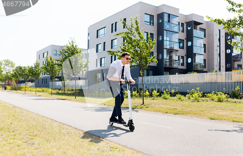 Image of young businessman riding electric scooter outdoors