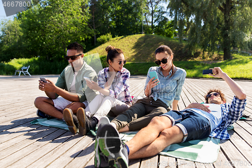 Image of friends with smartphones at summer park