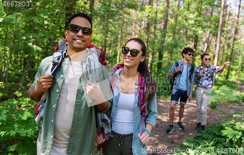 Image of group of friends with backpacks hiking in forest