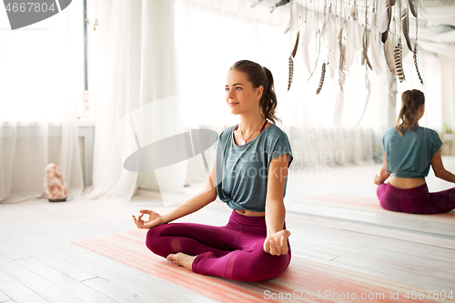 Image of woman meditating in lotus pose at yoga studio