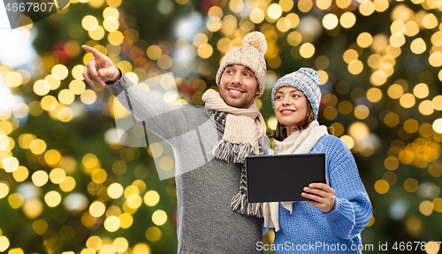 Image of couple with tablet computer over christmas lights