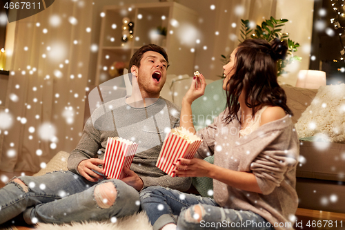 Image of happy couple eating popcorn at home