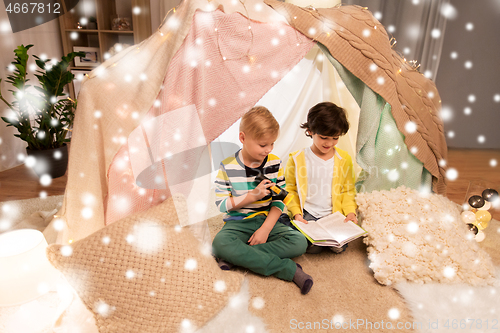 Image of happy boys reading book in kids tent at home