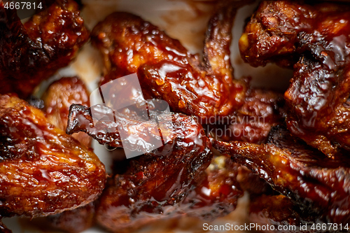 Image of Close up on Chicken wings in thick barbecue sauce. Served on white cast iron dish