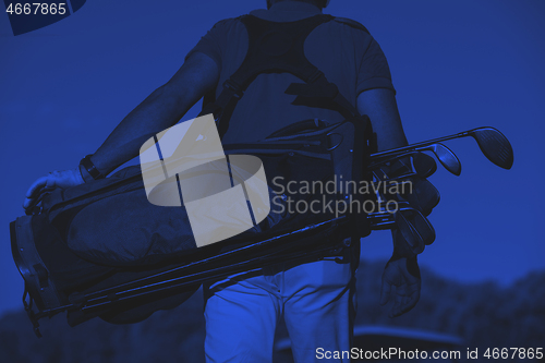 Image of close up of golfers back while   walking and carrying golf  bag