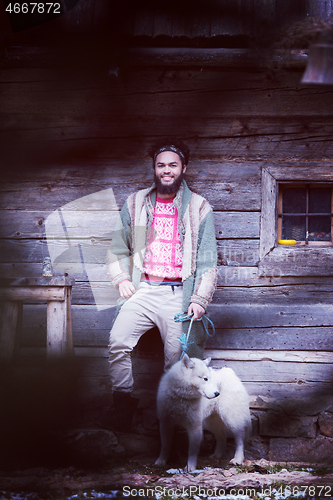 Image of hipster with dog in front of wooden house