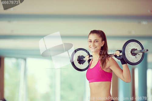 Image of young woman in fitness gym lifting  weights