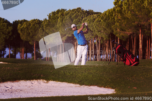 Image of golfer hitting a sand bunker shot on sunset