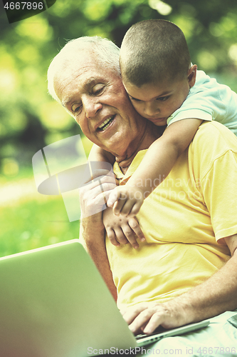 Image of grandfather and child using laptop