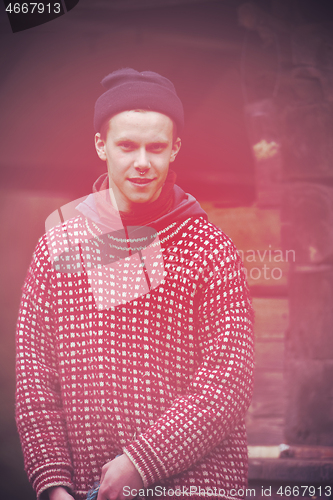 Image of young hipster in front of wooden house