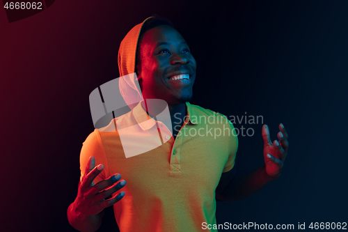 Image of Portrait of a happy young african american man smiling on black neon background