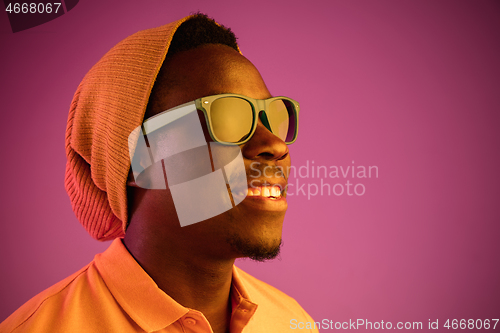 Image of Portrait of a happy young african american man smiling on black neon background