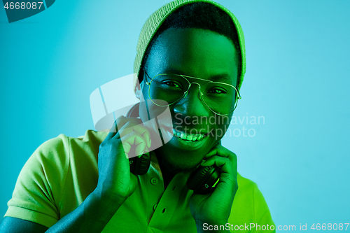 Image of Portrait of a happy young african american man smiling on black neon background