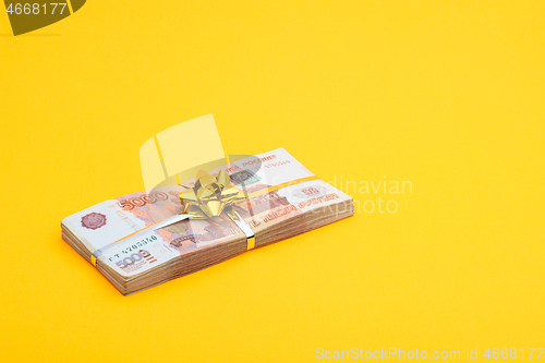 Image of On a yellow background lies a bundle of notes with a yellow ribbon and a bow