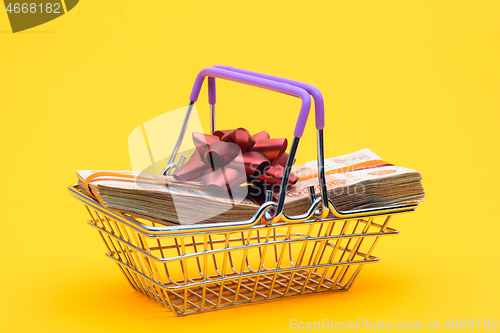 Image of In the grocery basket is a bundle of money with a red bow