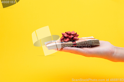 Image of Hand gives a pack of five thousandth bills on a yellow background