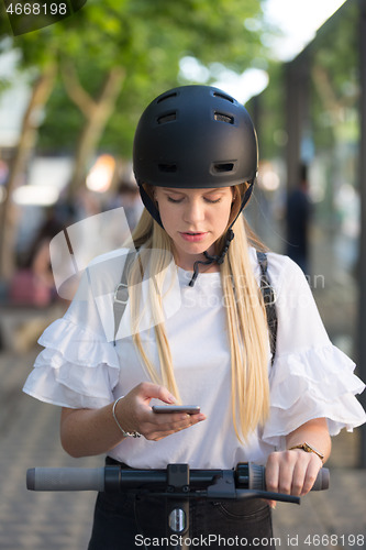 Image of Woman using smartphone and renting modern electric scooter with an application. Urban transport concept