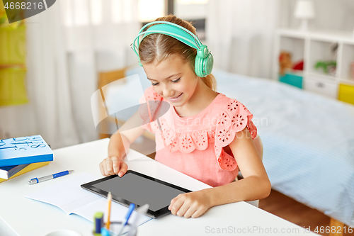 Image of girl in headphones with tablet computer at home