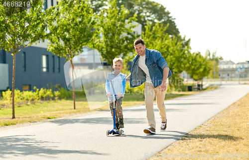 Image of happy father and little son riding scooter in city