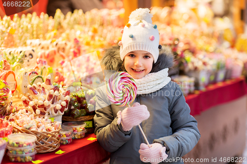 Image of girl with lollipop at christmas market candy shop