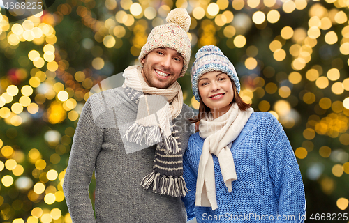 Image of happy couple in winter hats over christmas lights