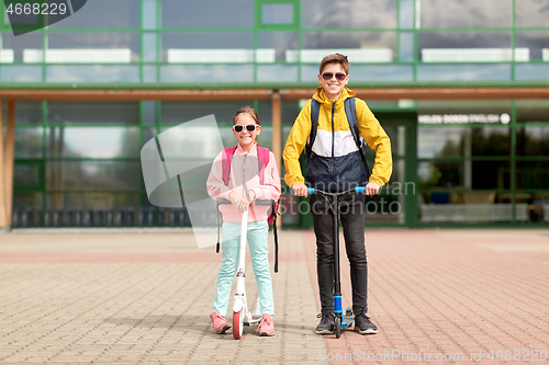 Image of happy school children with backpacks and scooters