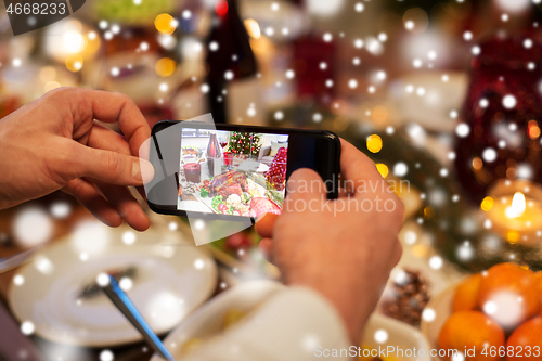 Image of hands photographing food at christmas dinner