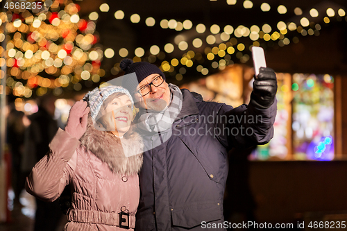 Image of senior couple taking selfie at christmas market