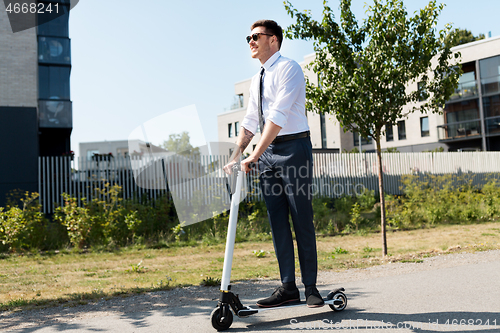 Image of young businessman riding electric scooter outdoors