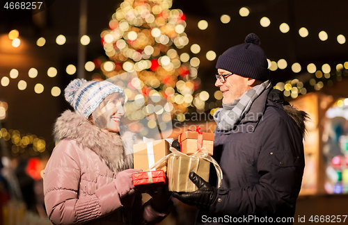 Image of happy senior couple with gift at christmas market