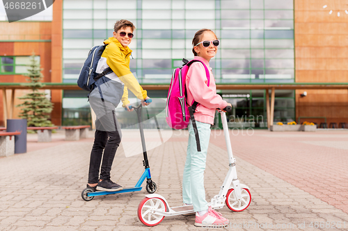 Image of school children with backpacks riding scooters