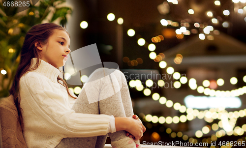 Image of sad girl sitting at home window on christmas