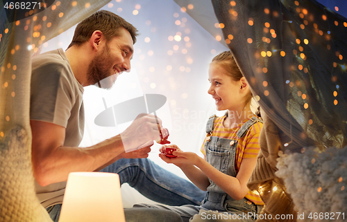 Image of family playing tea party in kids tent at home