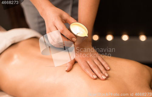 Image of back massage with hot oil candle at spa