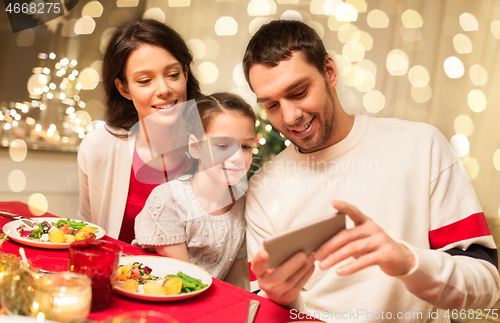 Image of family with smartphone having christmas dinner