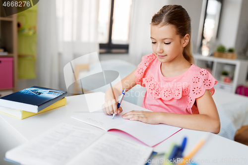 Image of student girl with book writing to notebook at home