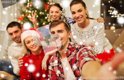 Image of friends celebrating christmas and taking selfie