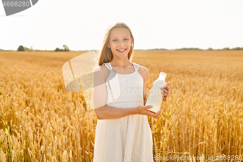 Image of happy girl with bottle of milk on cereal field