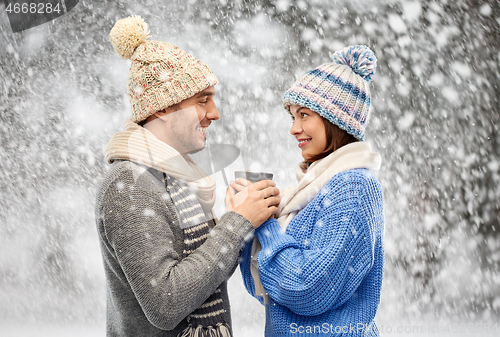 Image of happy couple in winter clothes holding one cup