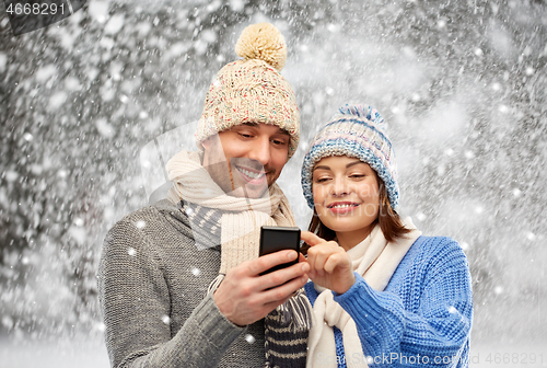 Image of happy couple in winter clothes with smartphone