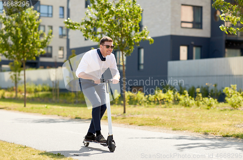 Image of young businessman riding electric scooter outdoors