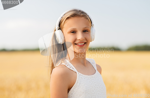 Image of happy girl in headphones on cereal field in summer