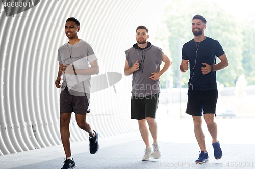 Image of male friends with earphones running outdoors