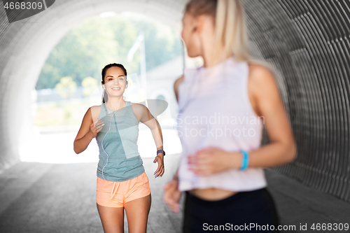 Image of women or female friends with earphones running