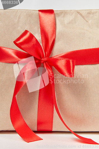 Image of Big red bow from silk ribbon on a gift box. Close-up view.